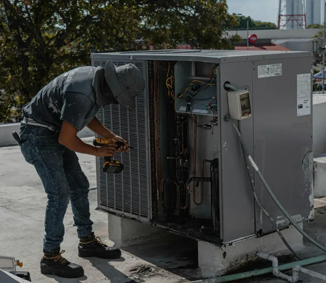 Technician repairing an HVAC unit fan motor with tools in hand