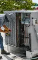 Technician working inside an outdoor HVAC unit on a rooftop