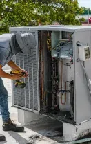 Technician working inside an outdoor HVAC unit on a rooftop