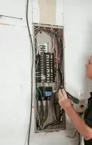 Technician repairing a wall-mounted air conditioner with tools in a home interior