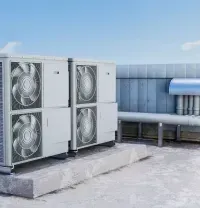 Rooftop industrial HVAC units with large fans and metal ductwork on a concrete pad.