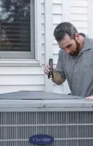 Technician inspecting a home air conditioner unit outside a house