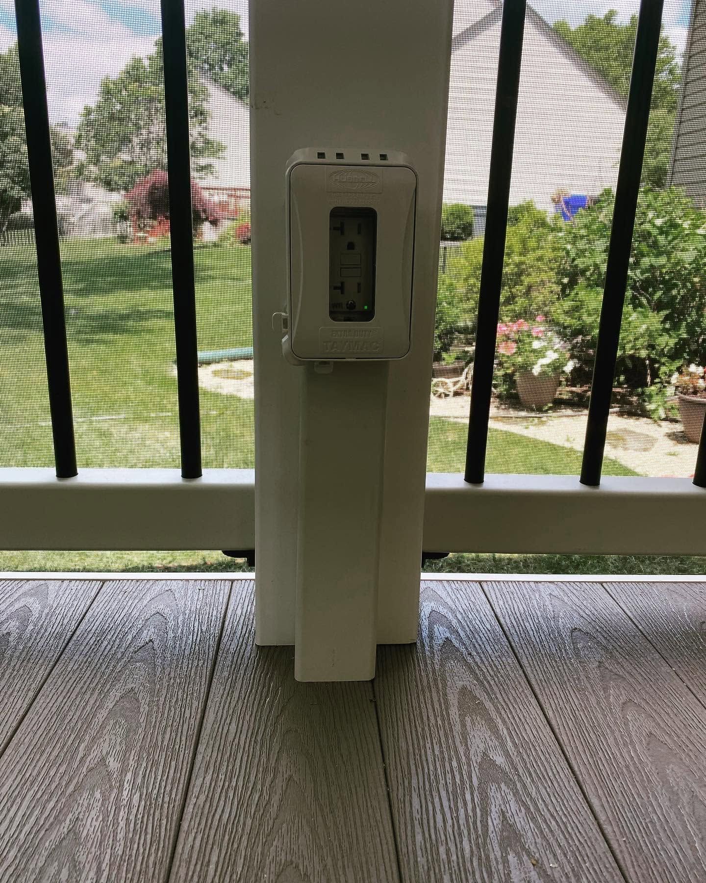 White electrical pedestal near a screened porch, with a garden and walkway visible outside.