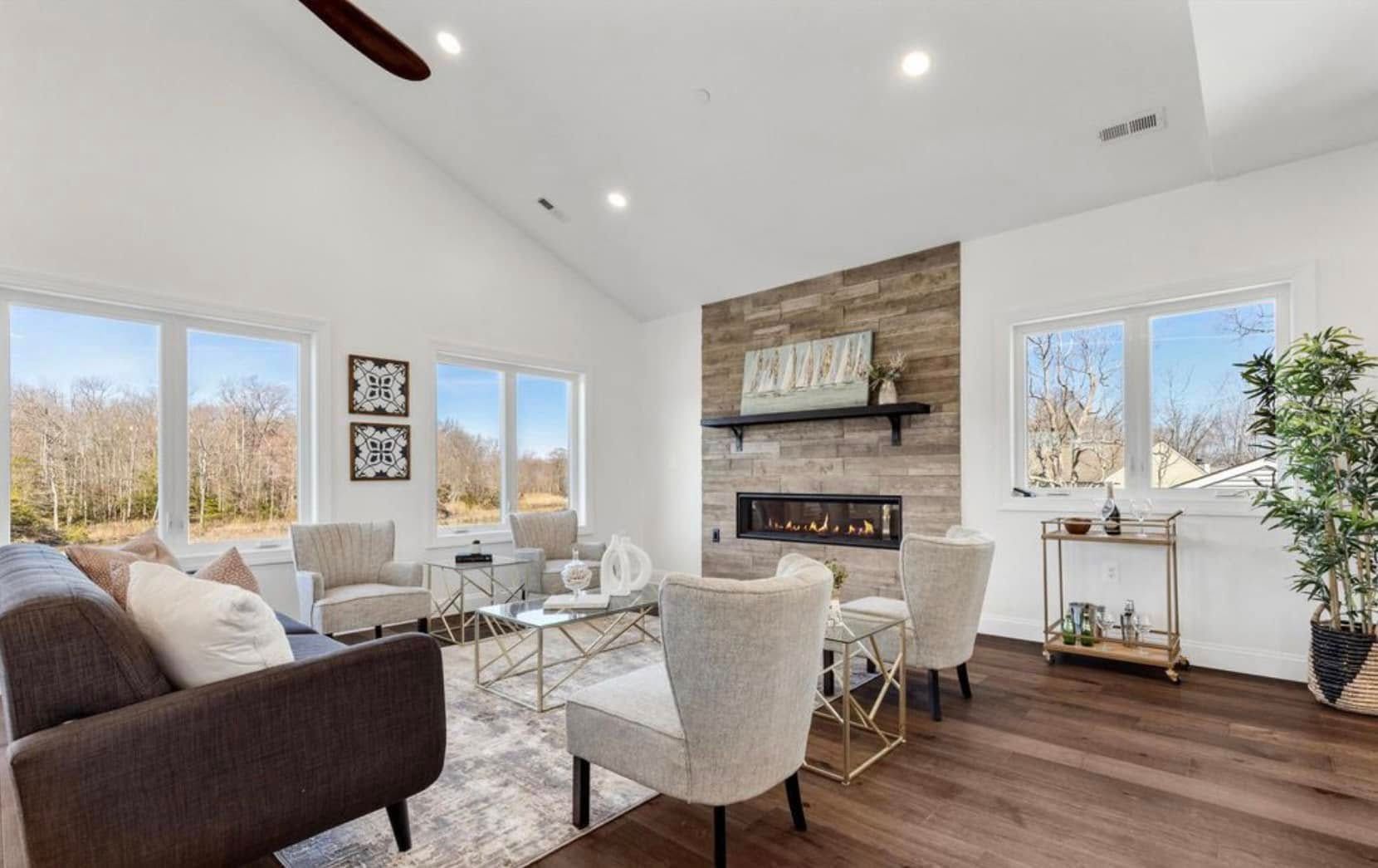 Bright modern living room with white walls, large windows, and a fireplace with wood accents