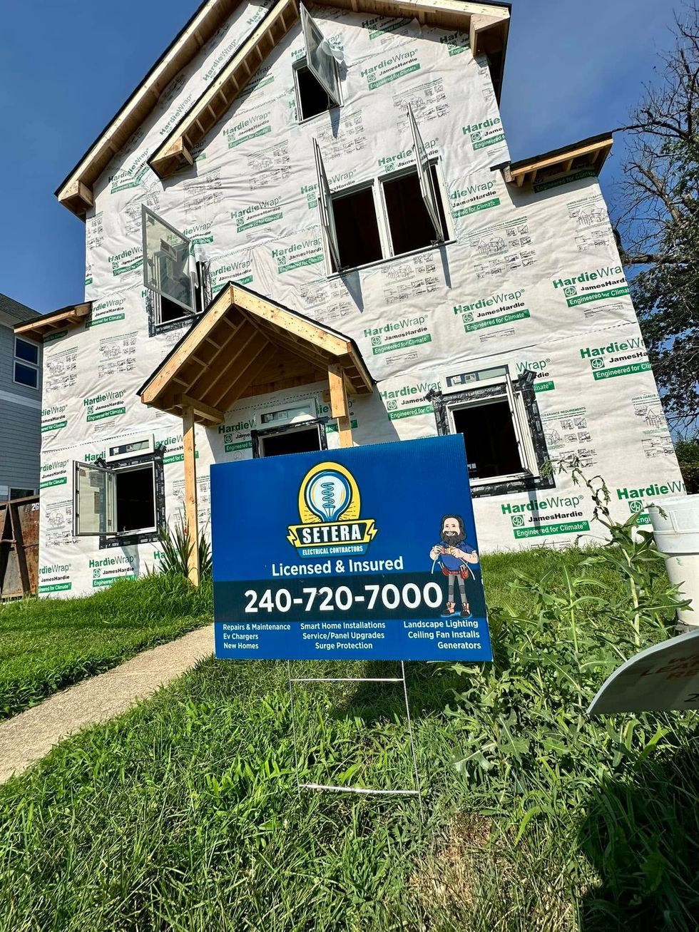 Partially built house with a blue yard sign reading “Mold? 240-720-7000” under a clear sky