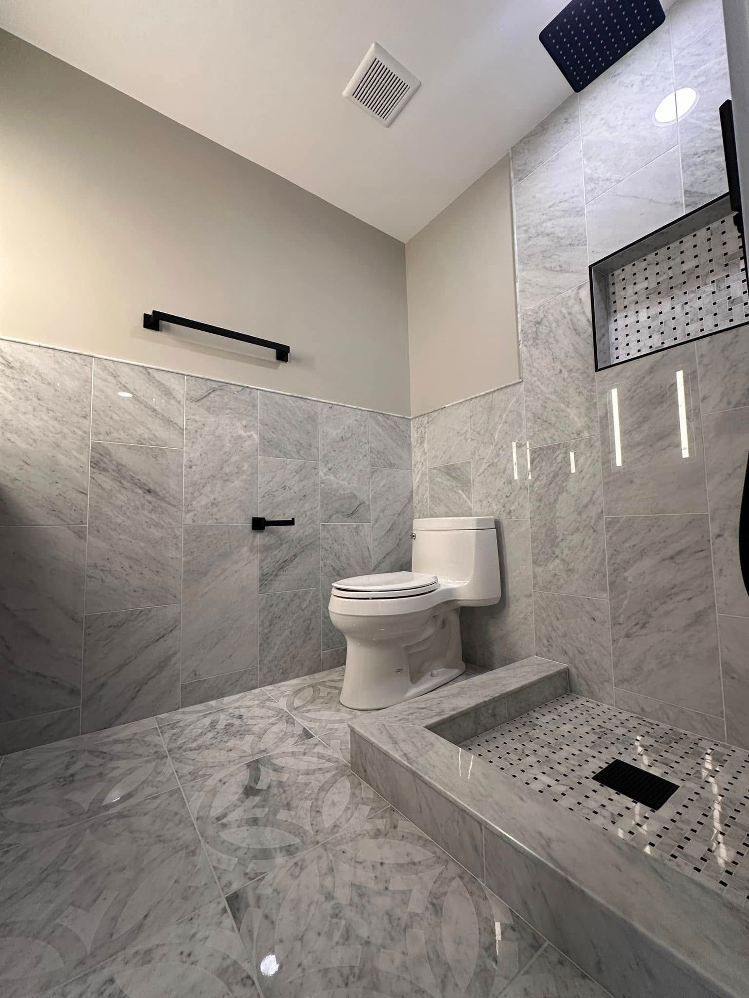 Marble-tiled bathroom with toilet, shower bench, and wall-mounted grab bar in a modern accessible stall