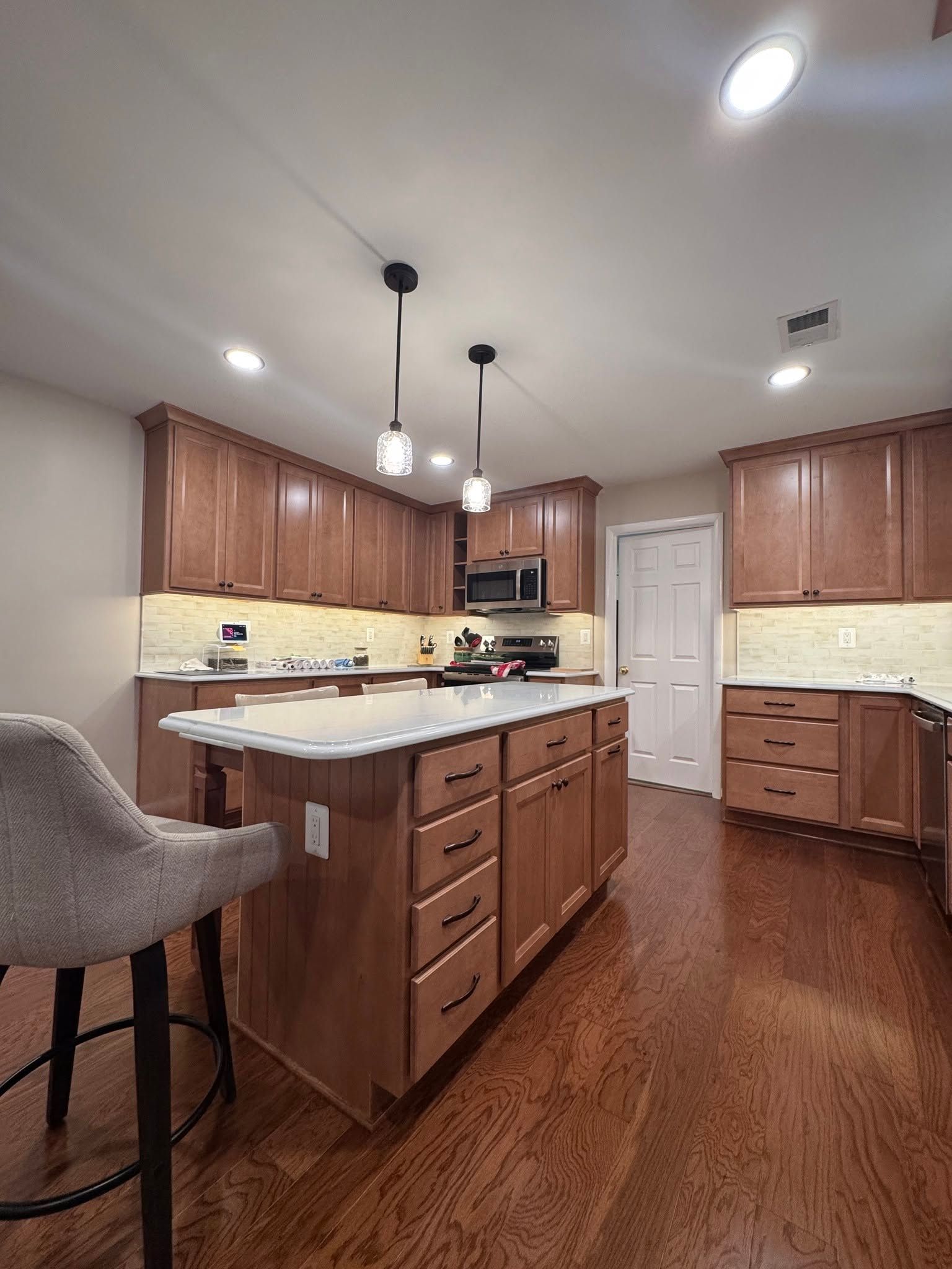 Modern kitchen with wood cabinets, white island countertop, and recessed ceiling lights