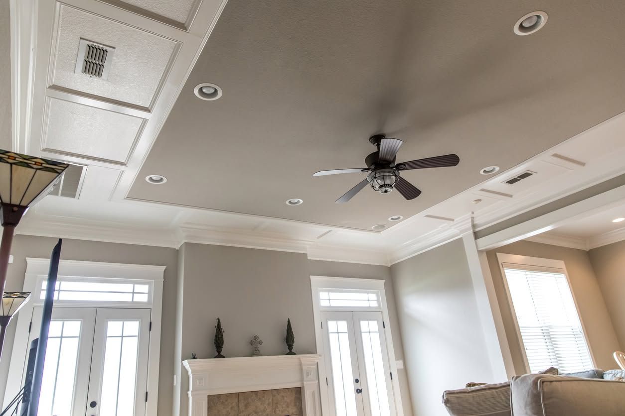 Bright living room with vaulted ceiling, ceiling fan, fireplace, and tall windows