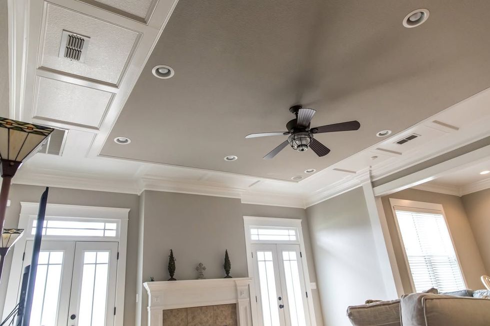Bright living room with white ceiling, recessed lights, ceiling fan, fireplace, and tall windows