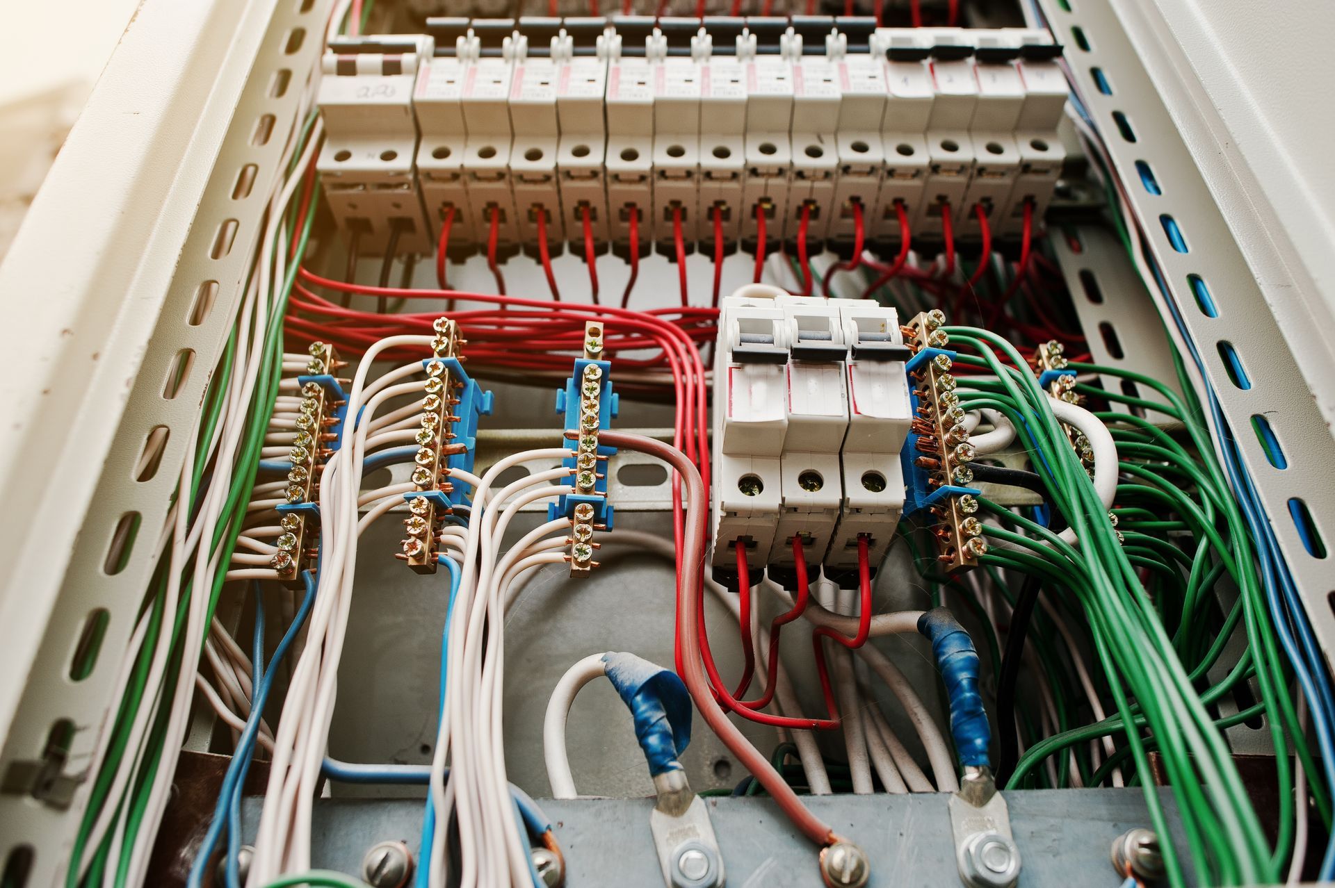 Electrical breaker panel with organized red, blue, and green wiring and circuit breakers
