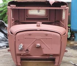 Rust-colored antique car body, front view. Hood, cab, and frame visible, primed and ready for paint.