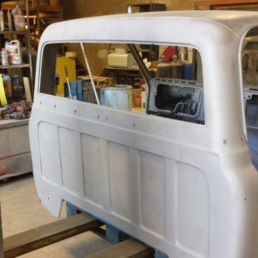 White truck cab rear section, window frame, interior details, workshop setting.