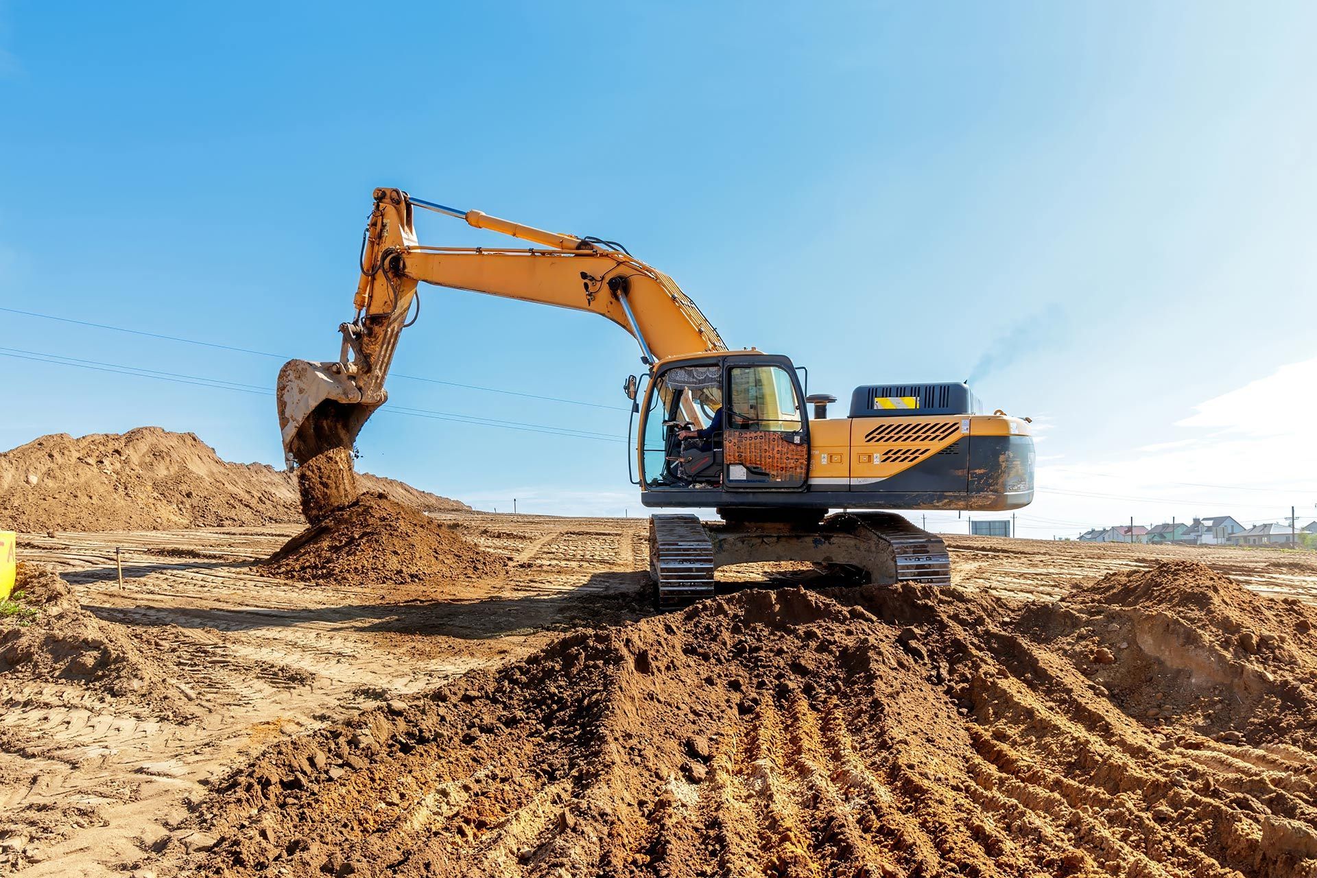 Excavator digging earth at a construction site under a clear blue sky