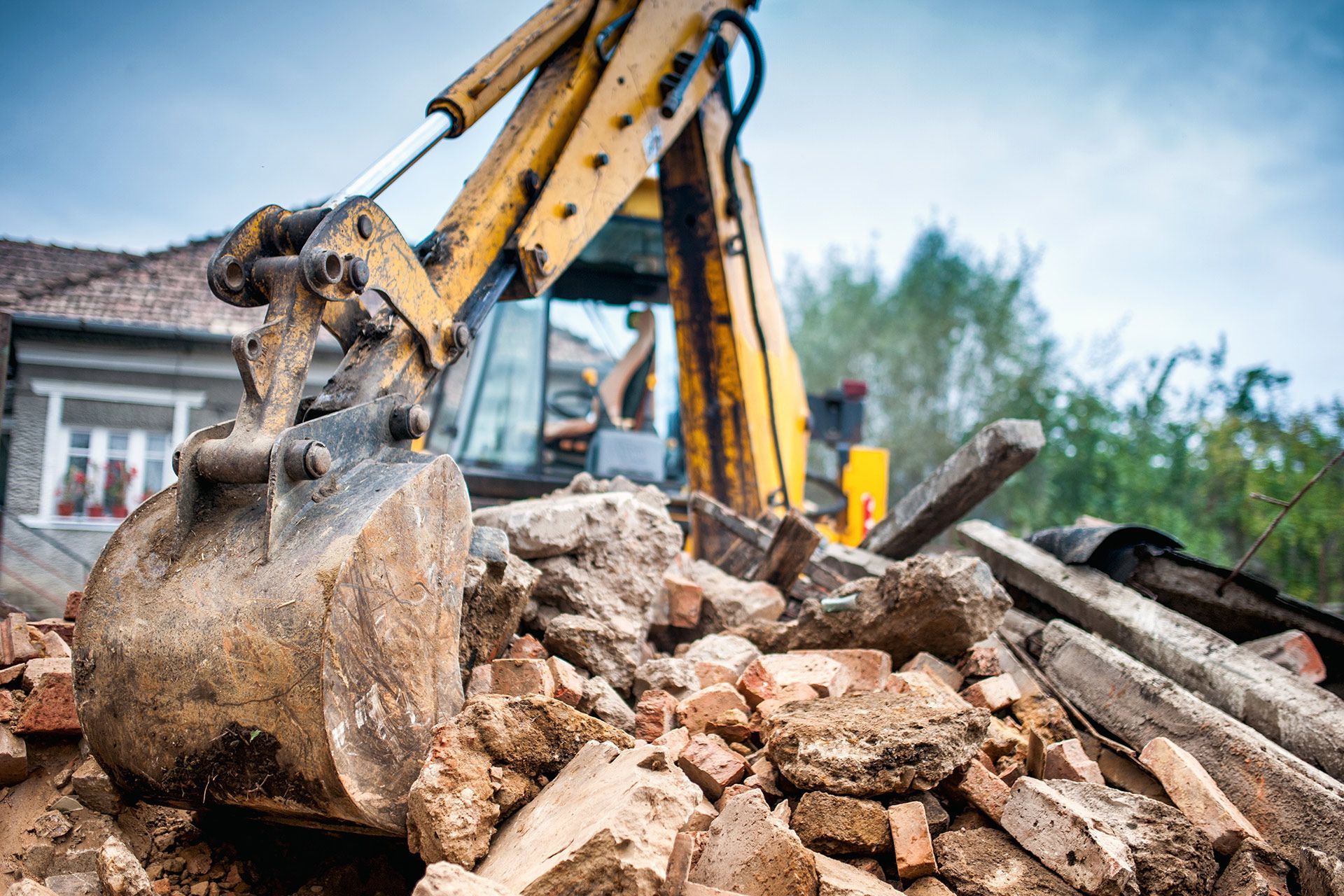 Yellow excavator clearing rubble at a demolition site