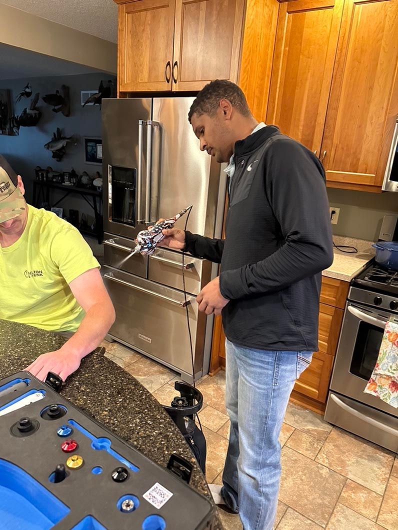 Two people in a kitchen looking at a smartphone near a granite counter and stainless-steel appliances