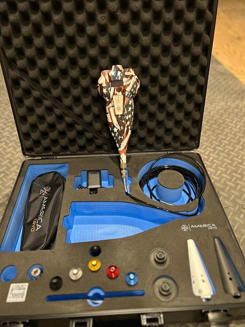 Open black foam case with a small drone, controller, cables, batteries, and white accessories inside.