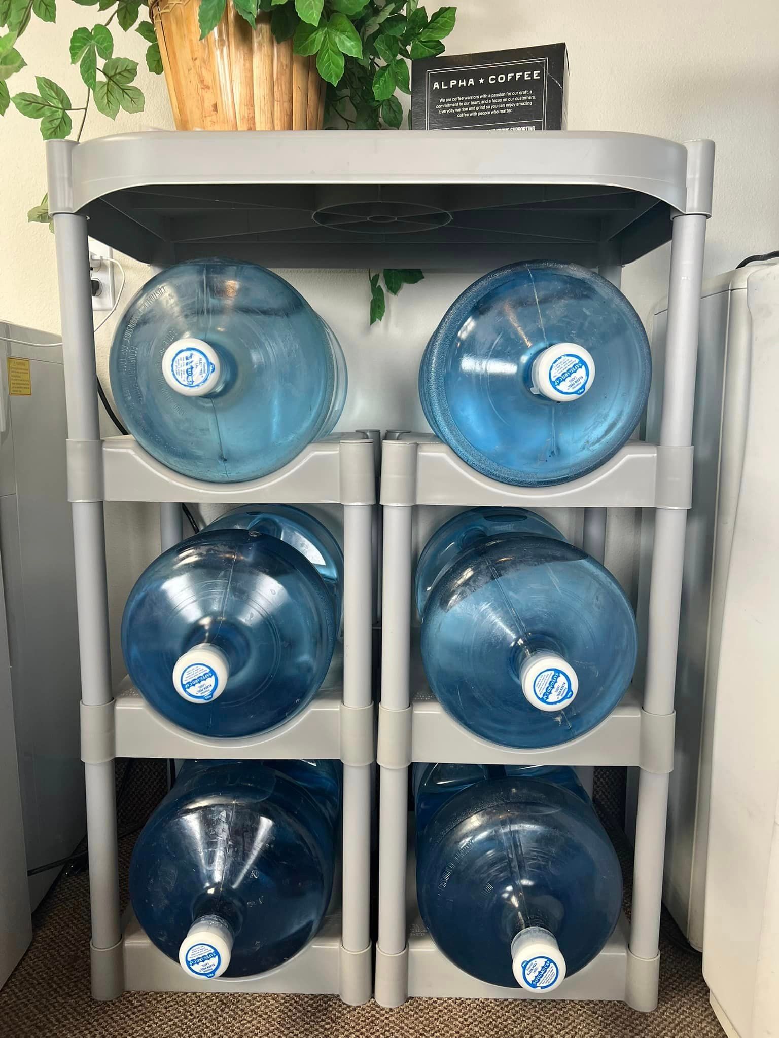 Four water bottles are stacked on top of each other on a shelf.