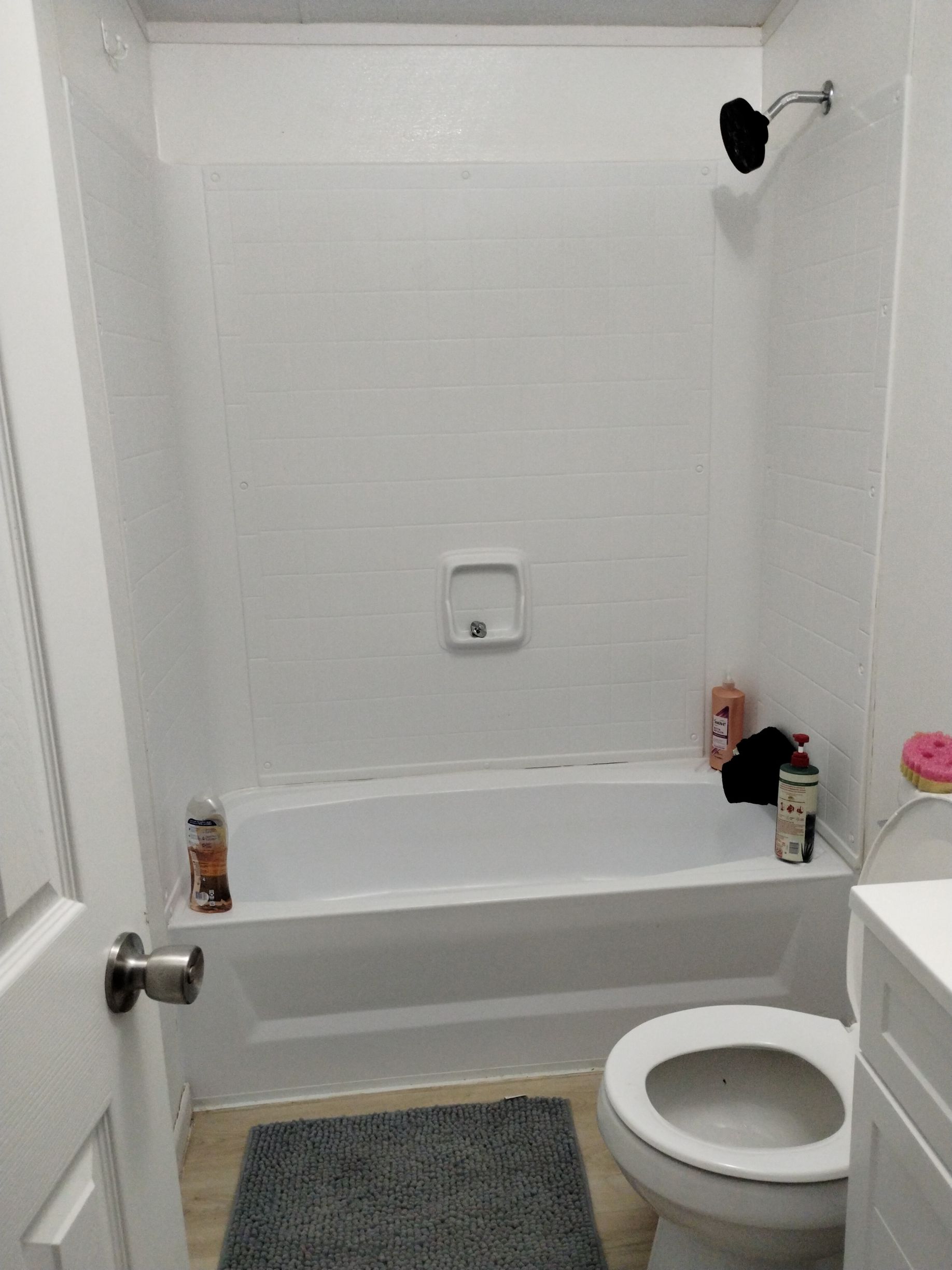 Small white bathroom with bathtub, toilet, and toiletries.
