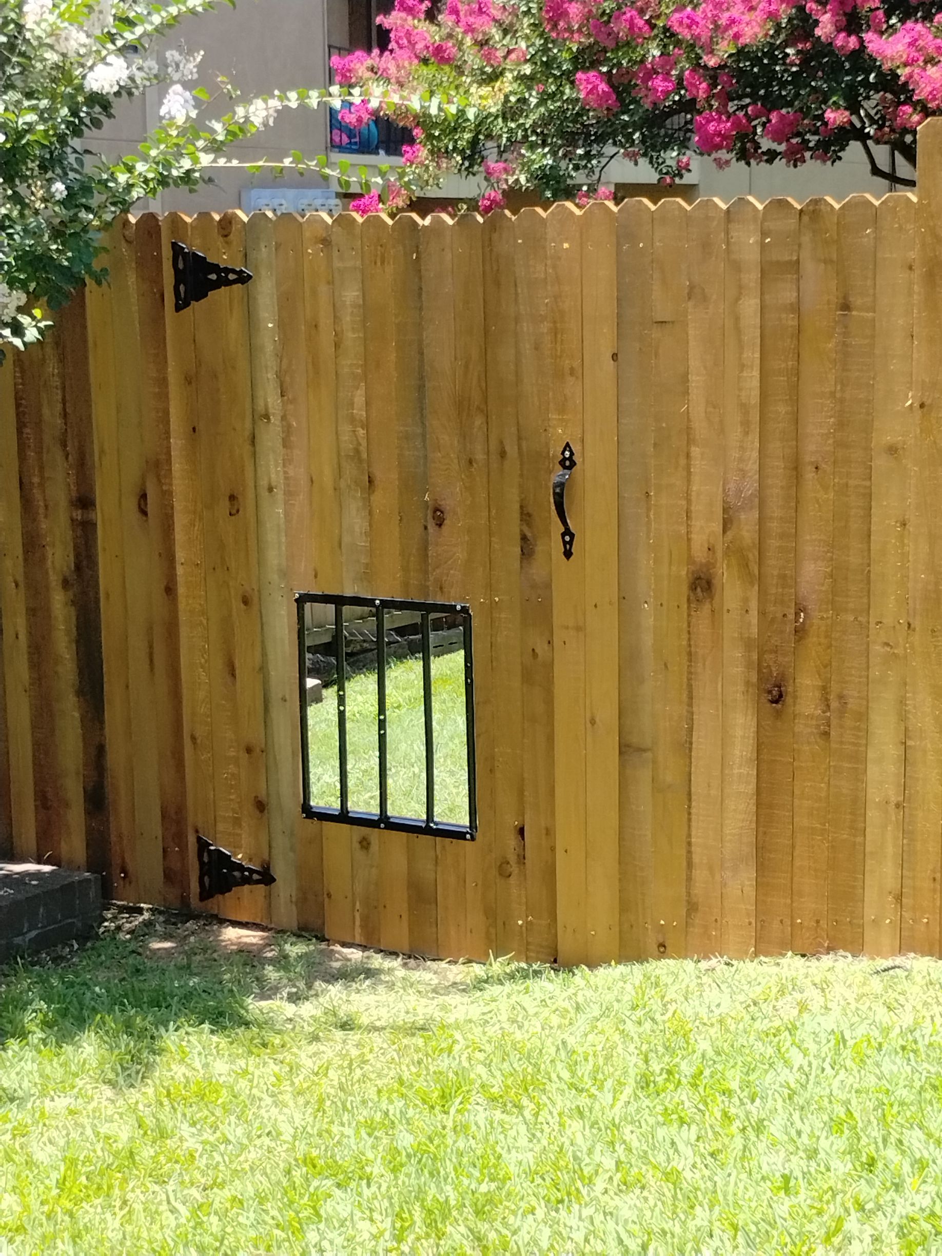 Wooden fence with a small, barred window and gate.