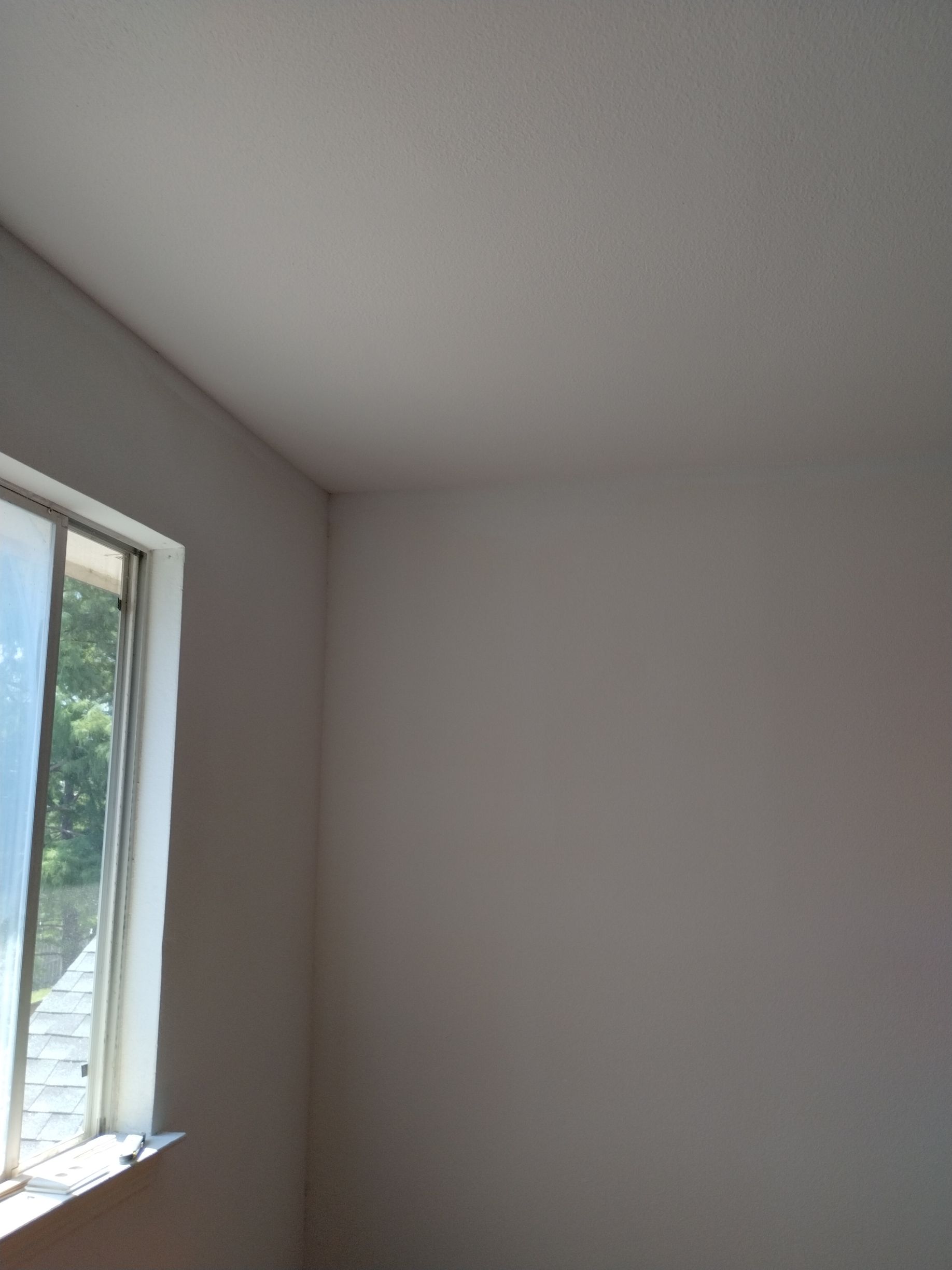 Interior corner of a room with a window. Light gray walls and ceiling.