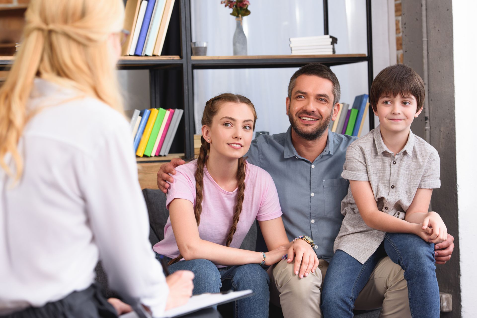 Counselor meeting with a seated family in a bright office, with shelves and books in the background