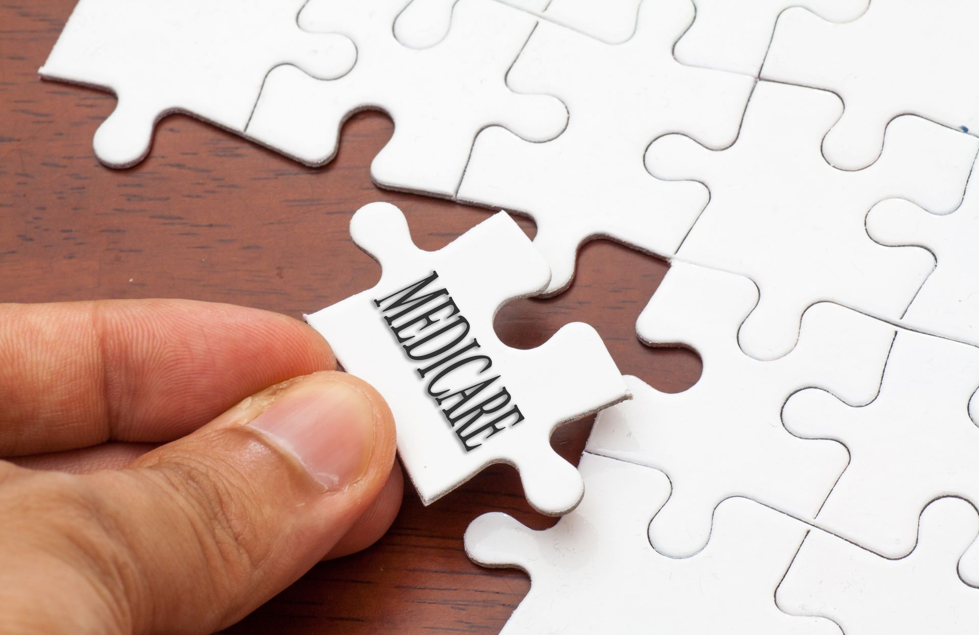 Hand placing a puzzle piece labeled Medicare into a white puzzle