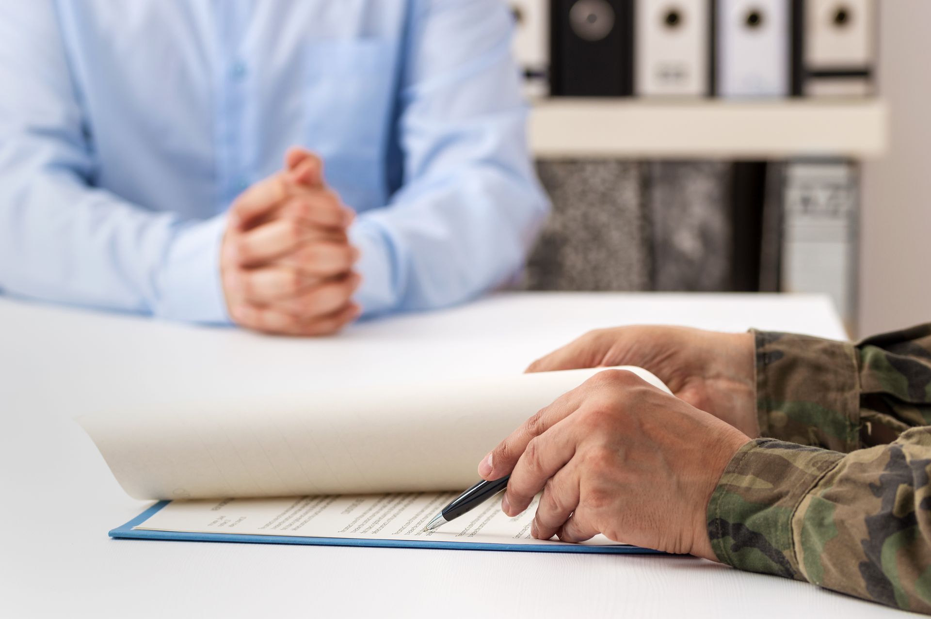 Hands reviewing a document across a white table in an office setting