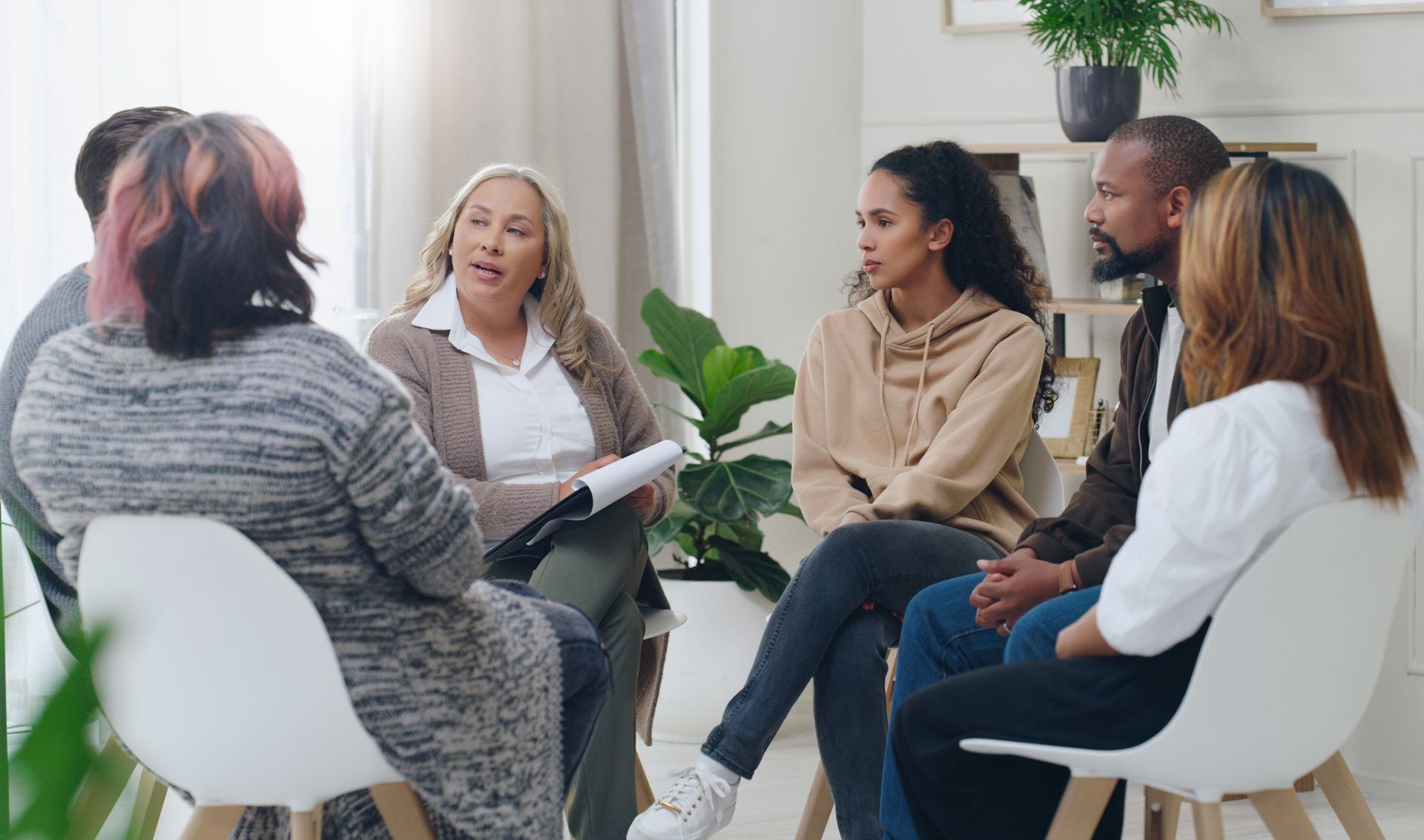 Small group seated in a bright room, talking in a circle during a discussion session.