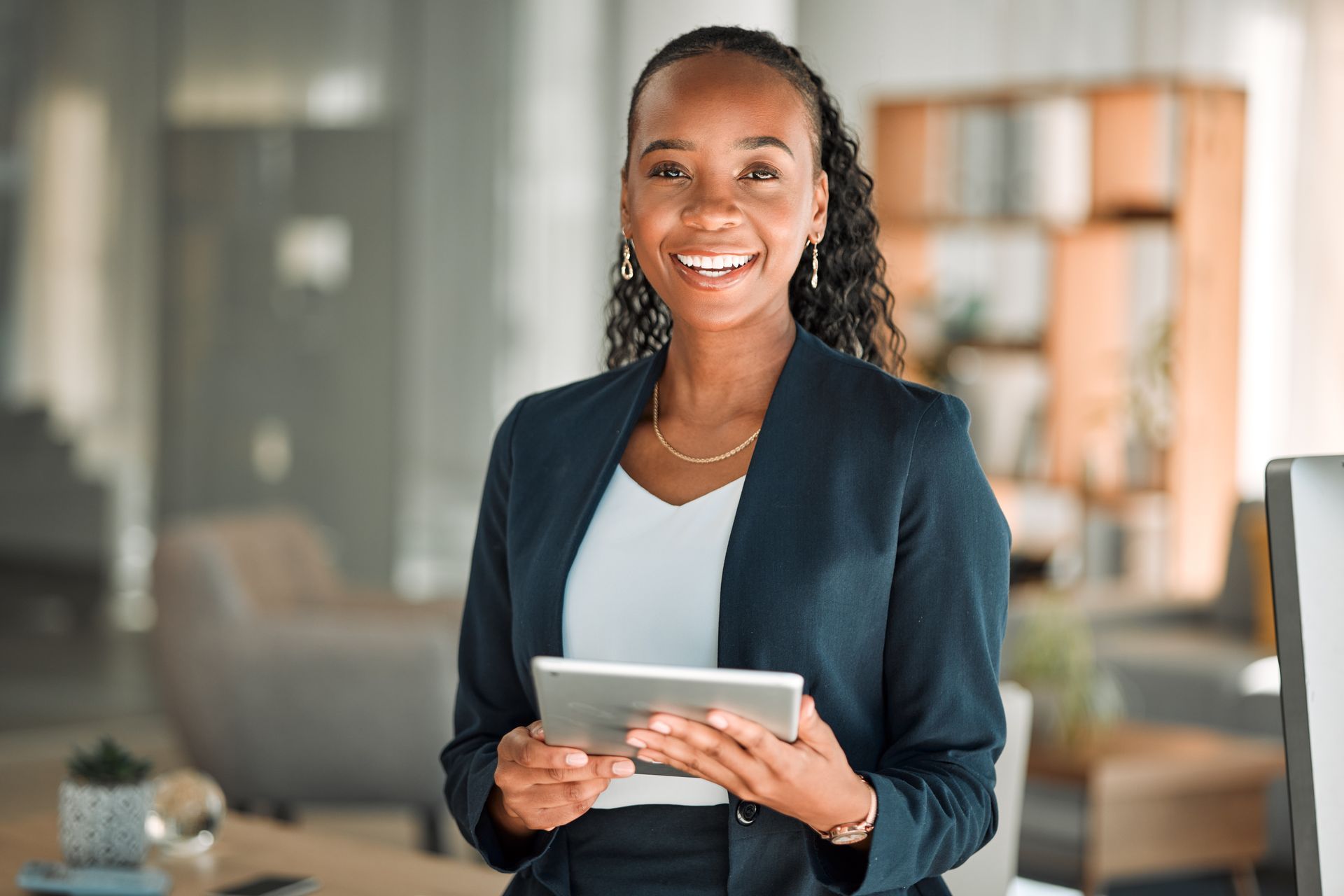 Smiling professional holding a tablet in a modern office setting