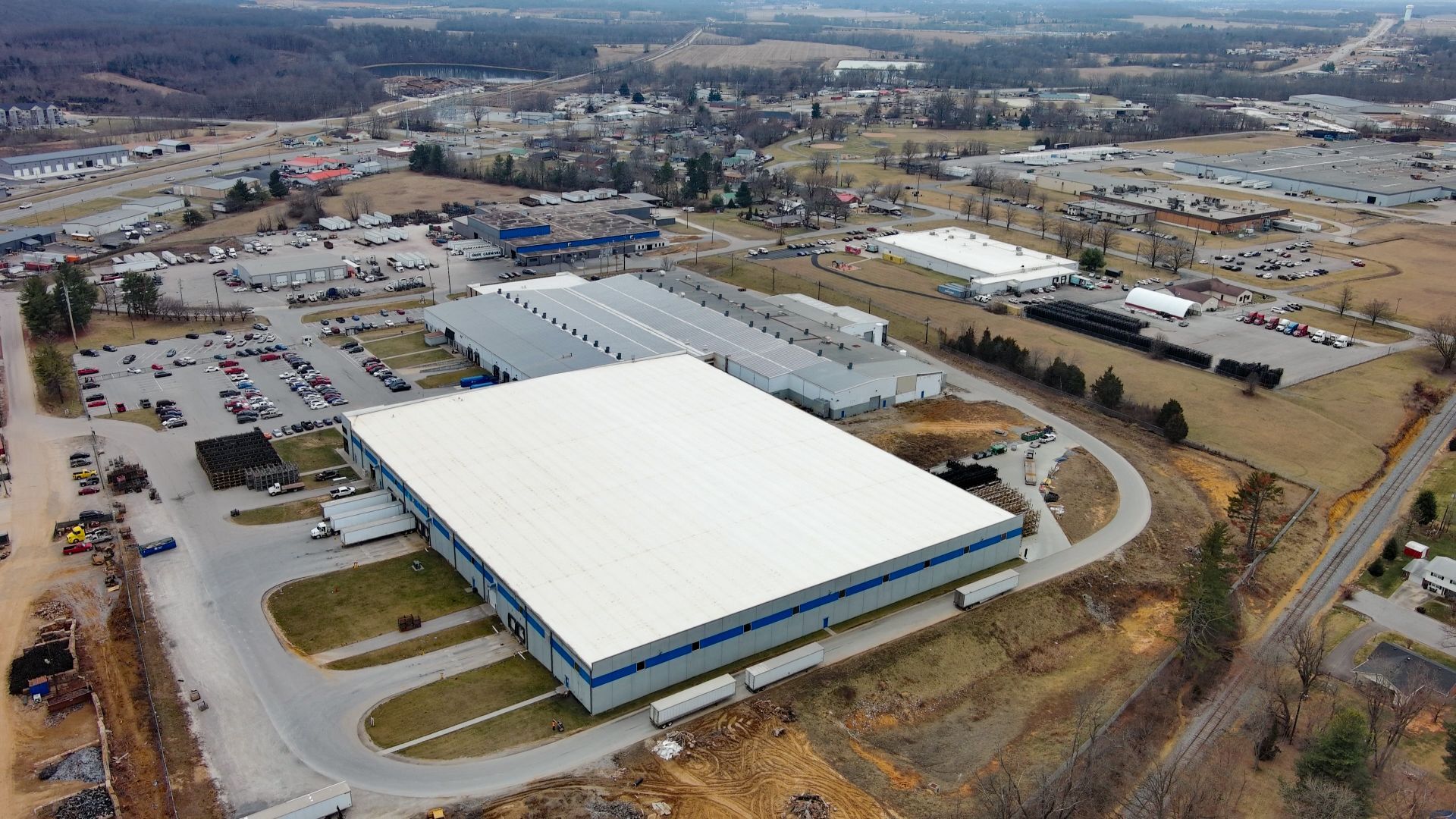 Aerial view of a large industrial building with a light-colored roof.