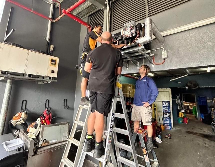 A Group of Men Are Working on A Machine in A Garage — Recharged Air & Electrical in Innisfail, QLD