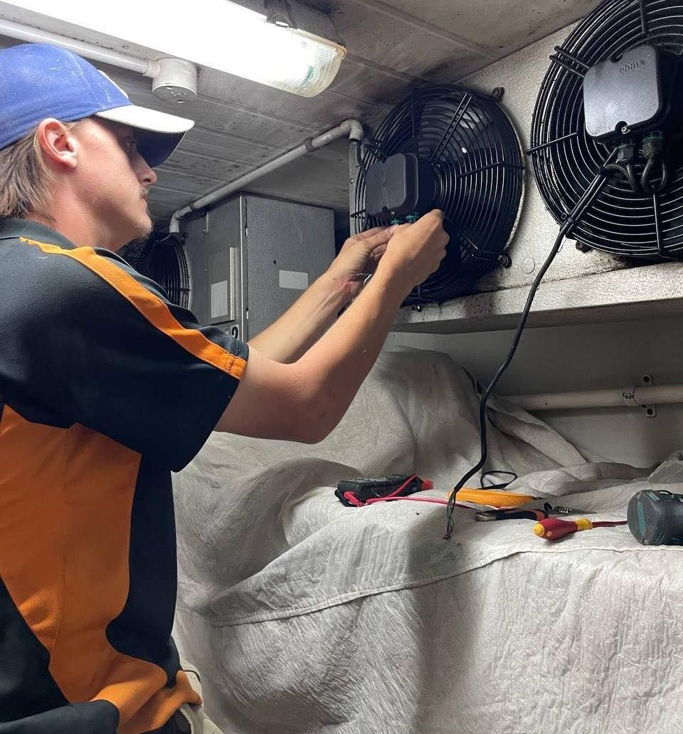 A Man in A Blue Hat Is Working on A Fan — Recharged Air & Electrical in Innisfail, QLD