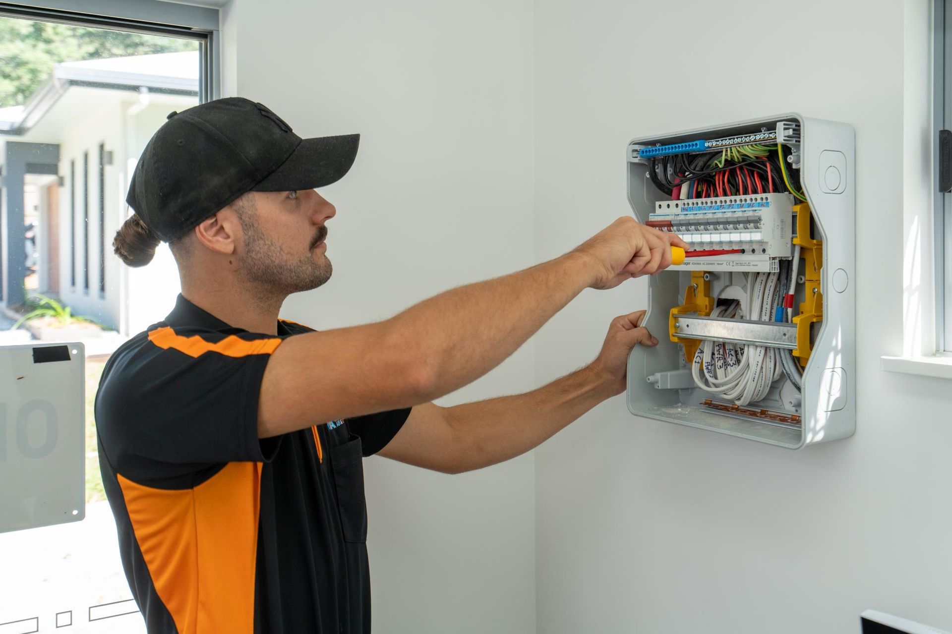 A Man Is Working on An Electrical Box on A Wall — Recharged Air & Electrical in Innisfail, QLD