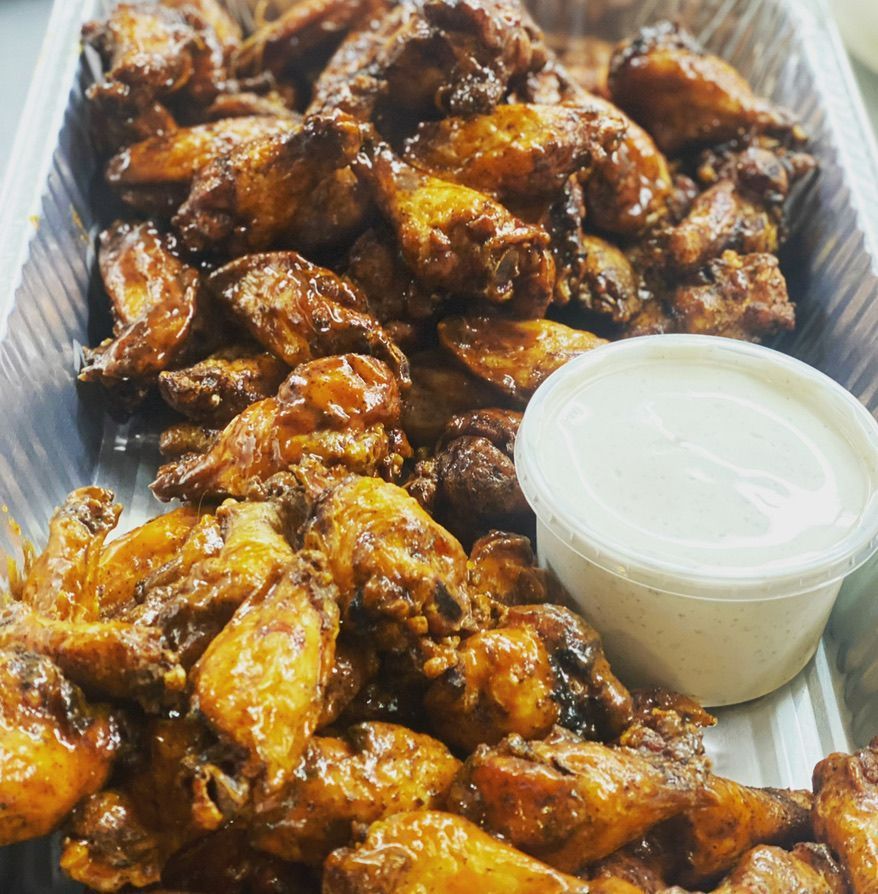 A tray of chicken wings with a side of dipping sauce.