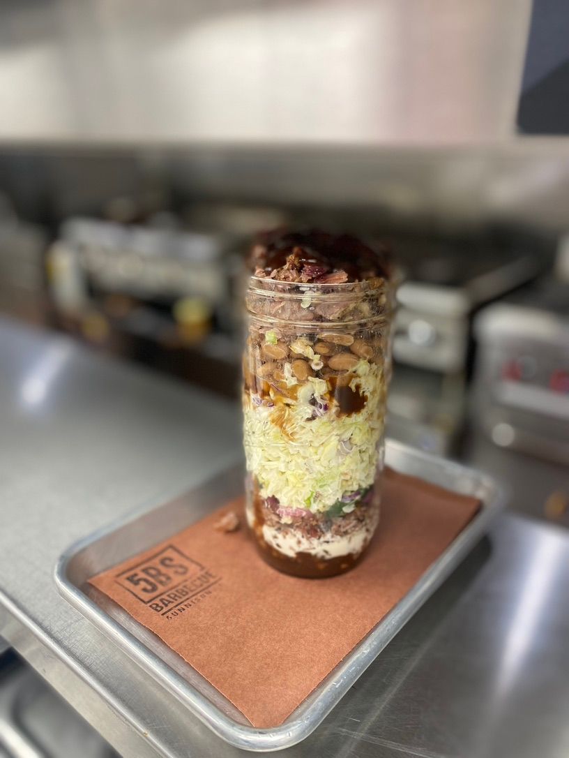 A mason jar filled with food is sitting on a tray.