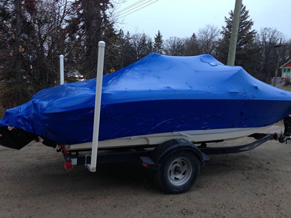 A boat is wrapped in a blue tarp on a trailer