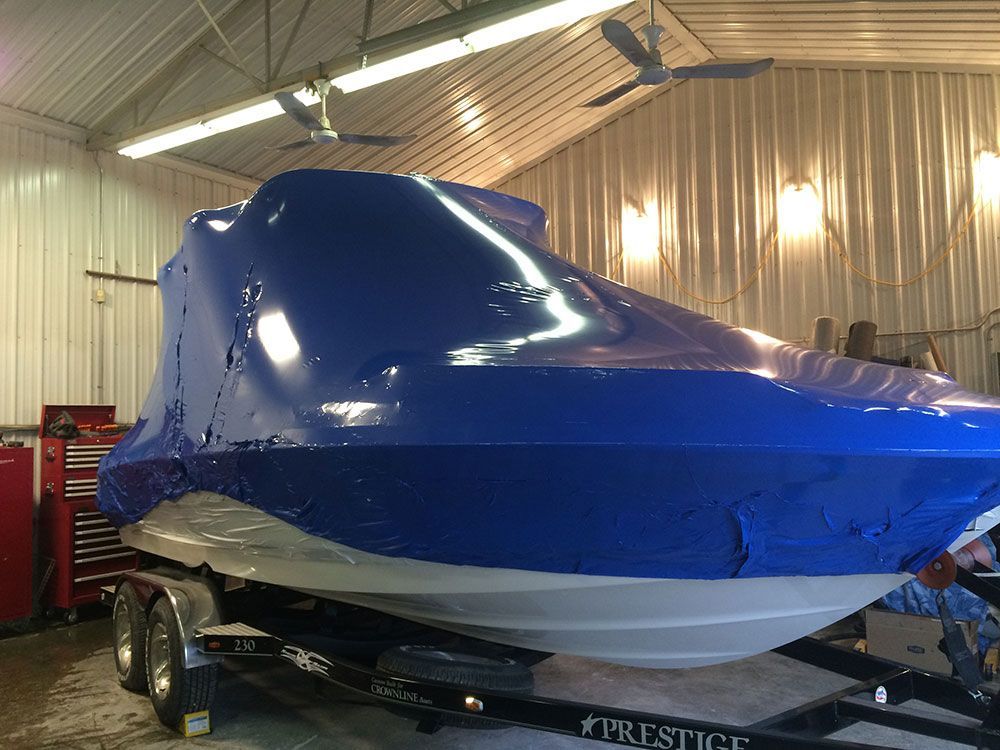 A blue boat is sitting on a trailer in a garage.