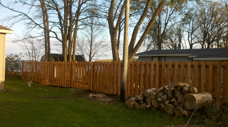 A wooden fence with a pile of logs in front of it