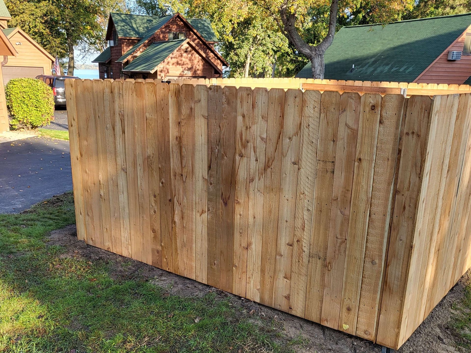 Large wooden privacy fence beside a driveway and green lawn in a residential yard