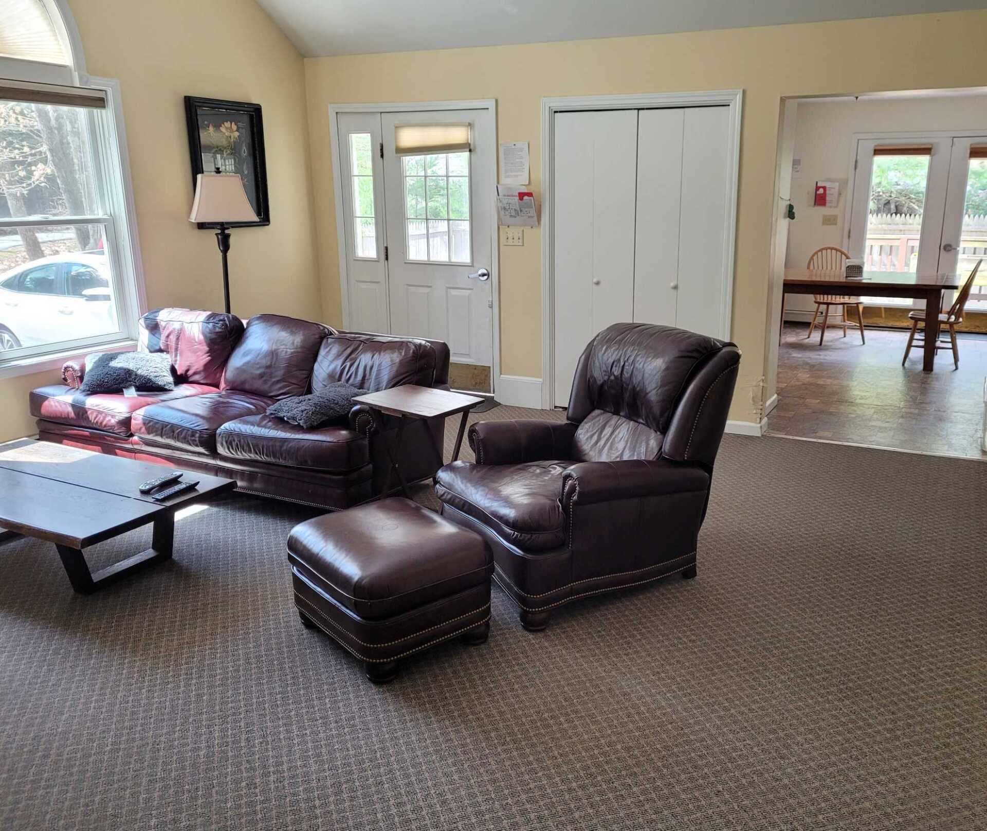 A living room with a couch , chair , ottoman and coffee table.
