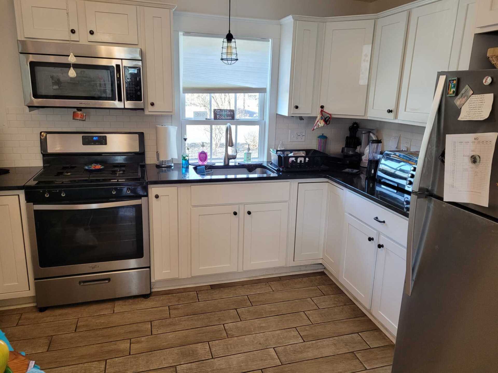 A kitchen with white cabinets , stainless steel appliances , and a refrigerator.