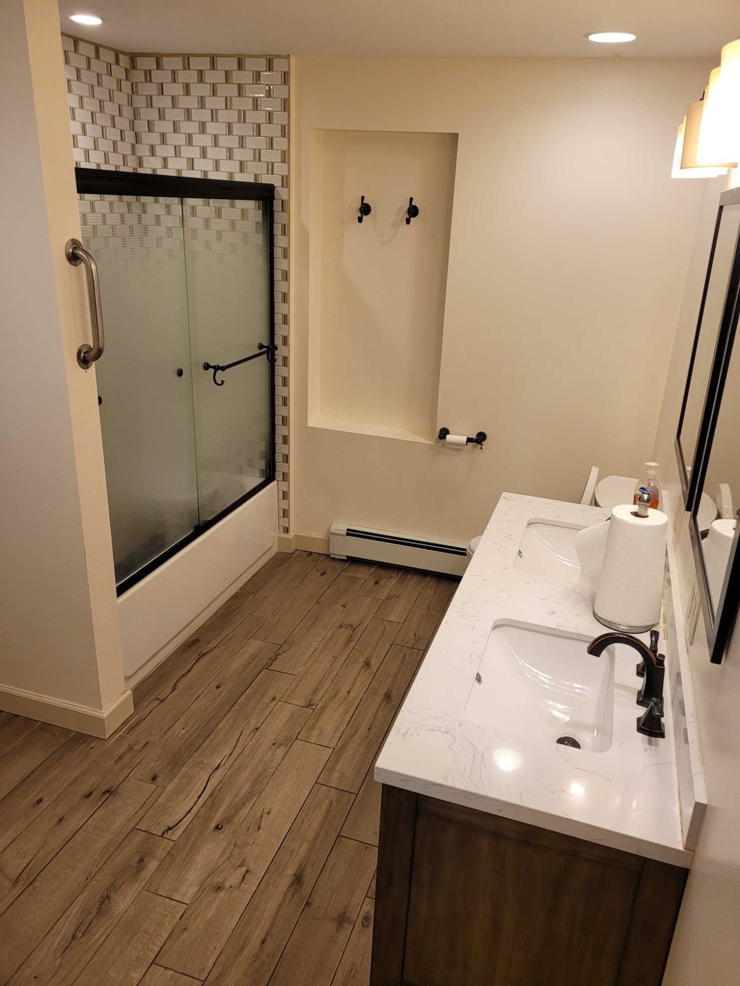 A bathroom with a sink , mirror and shower.
