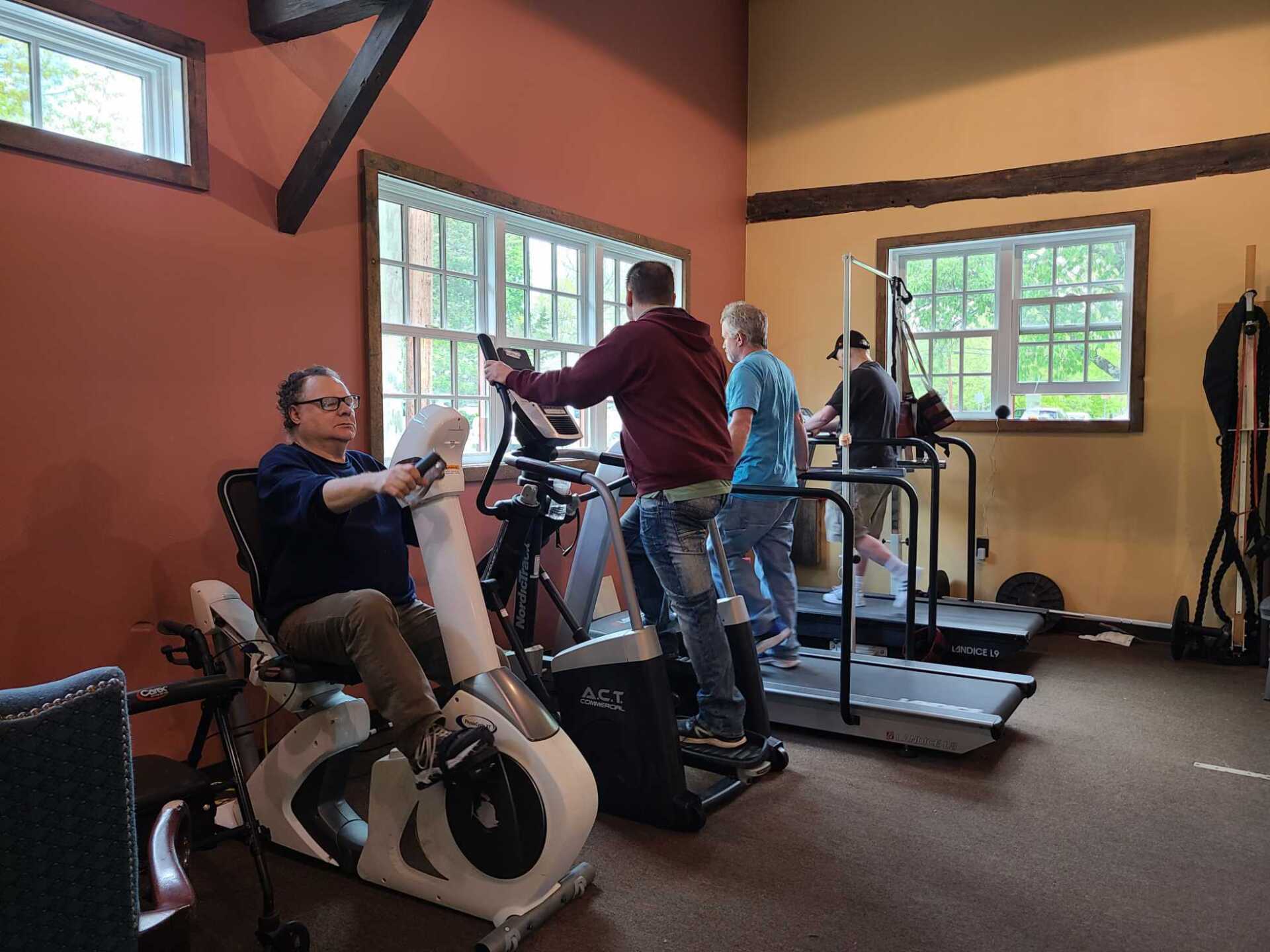 A group of people are using exercise bikes and treadmills in a gym.