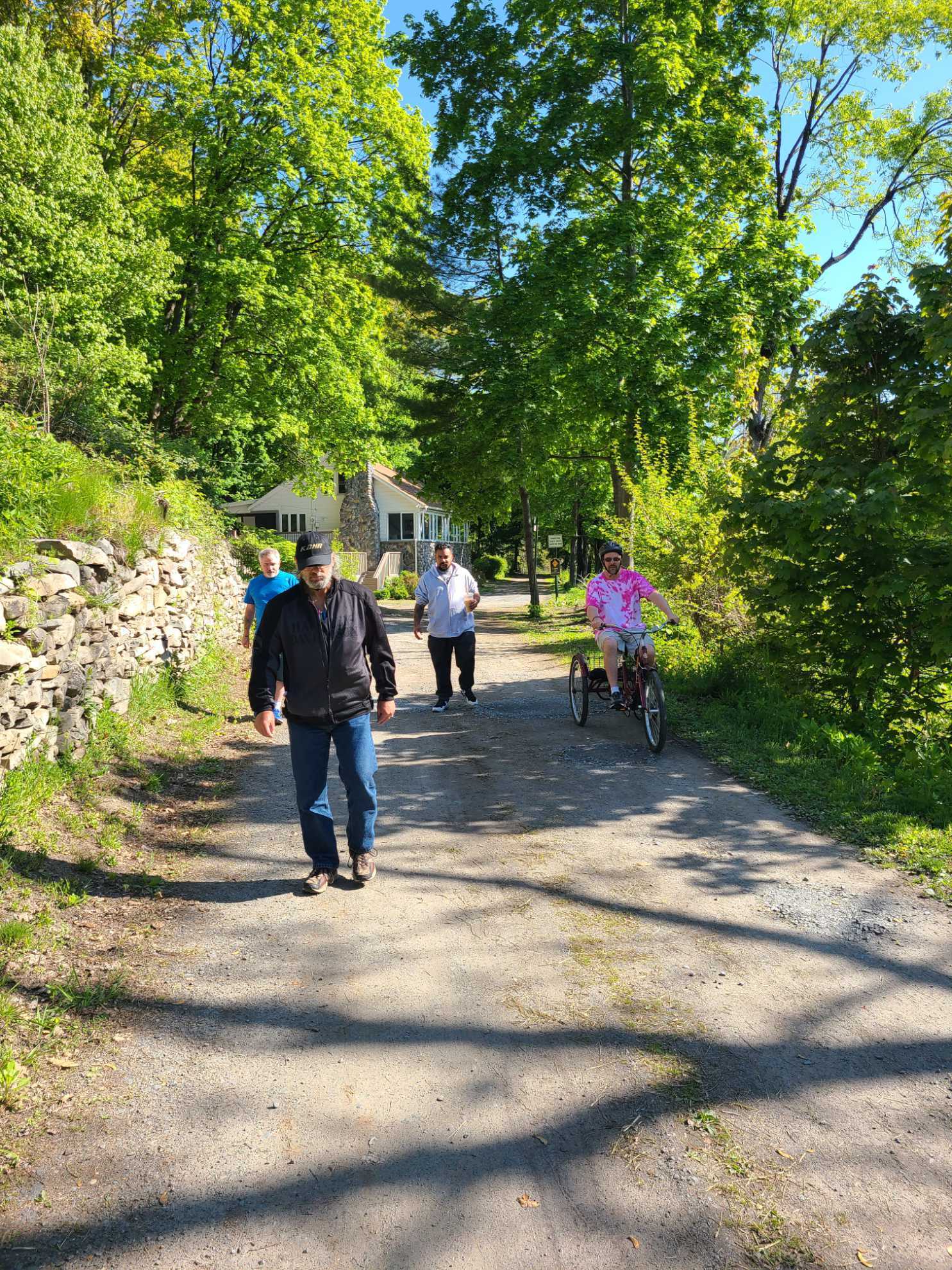 A group of people are walking down a dirt road.