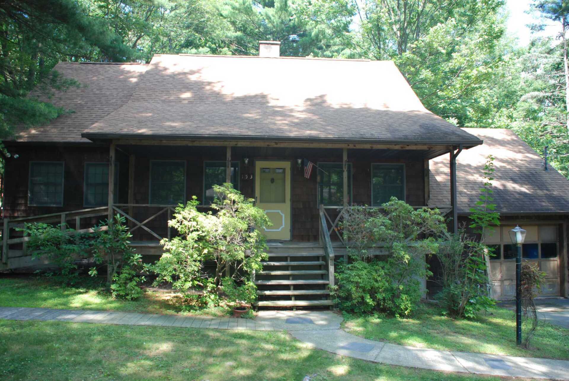 A house with a porch and stairs is surrounded by trees