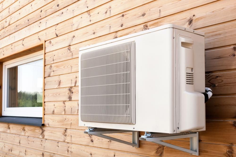 A White Air Conditioner is Mounted on the Side of a Wooden House — The Cool Guys In Palmerston, NT