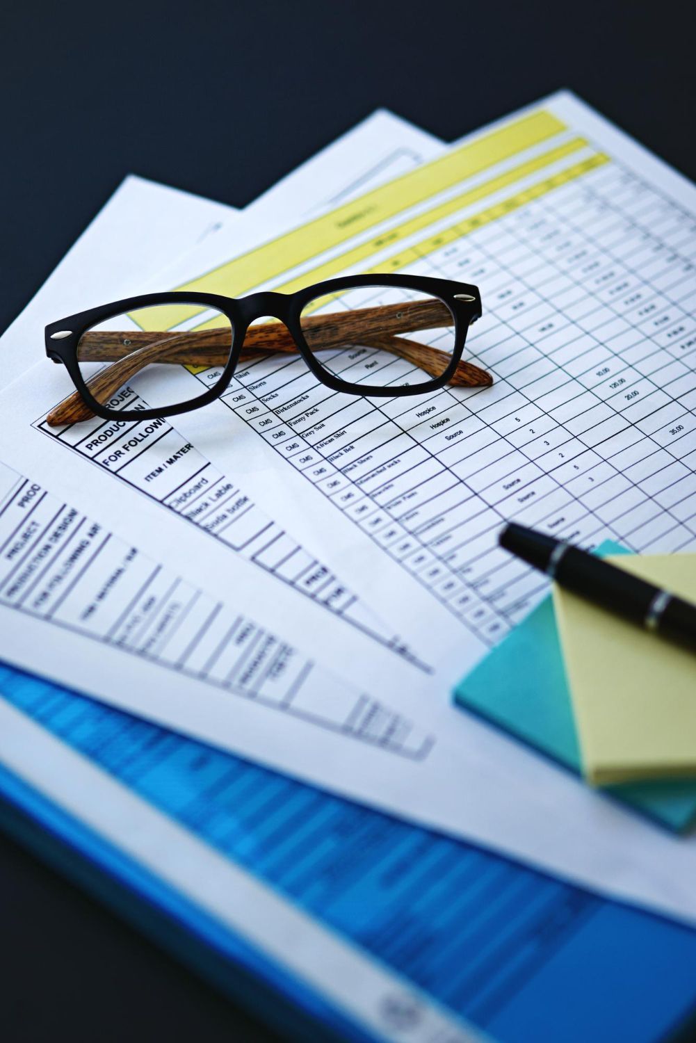 Eyeglasses on accounting sheets with pen and sticky notes.