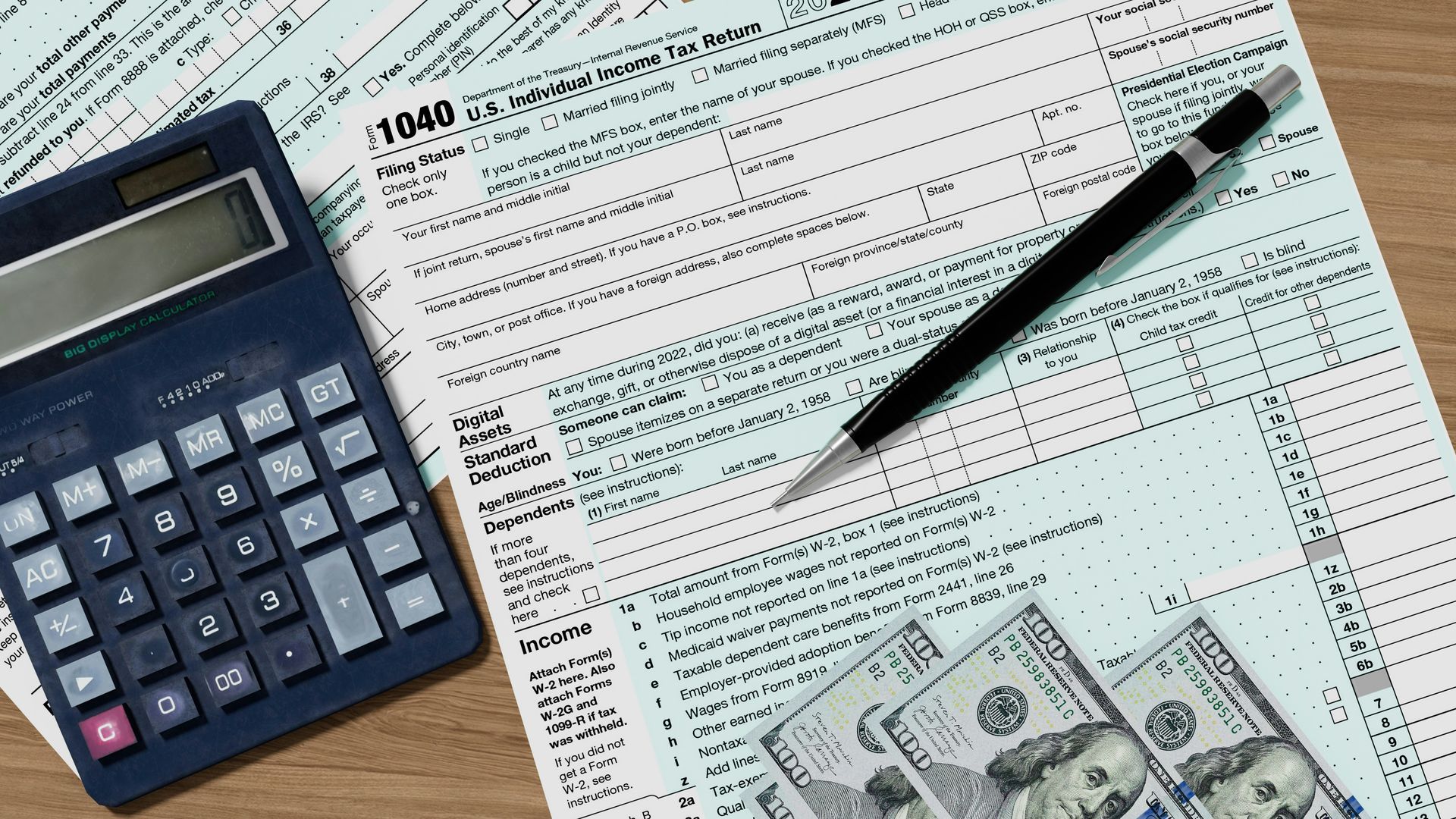 Calculator, pen, tax forms, and cash on a desk, representing financial and tax preparation.