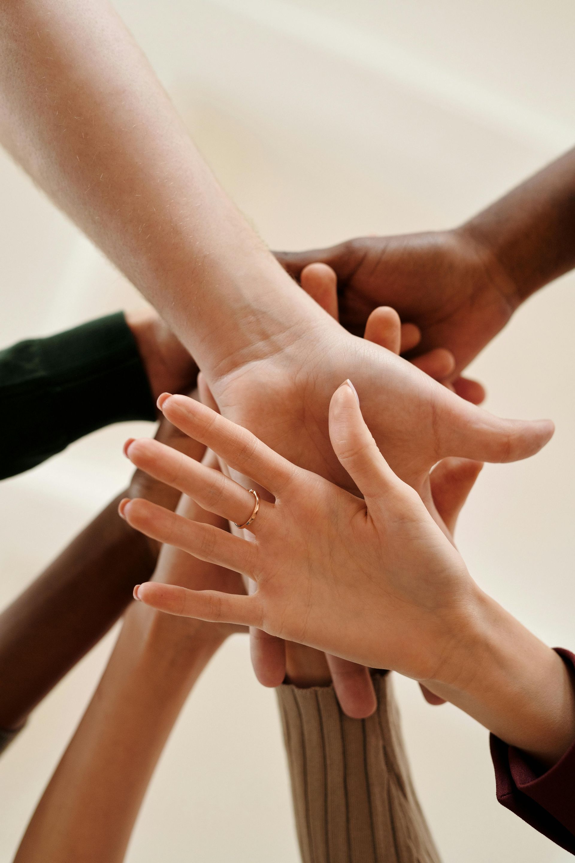 Three hands stacked together in a team huddle over a white background