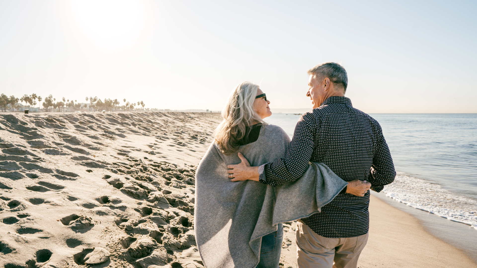 A man and a woman are walking on the beach.